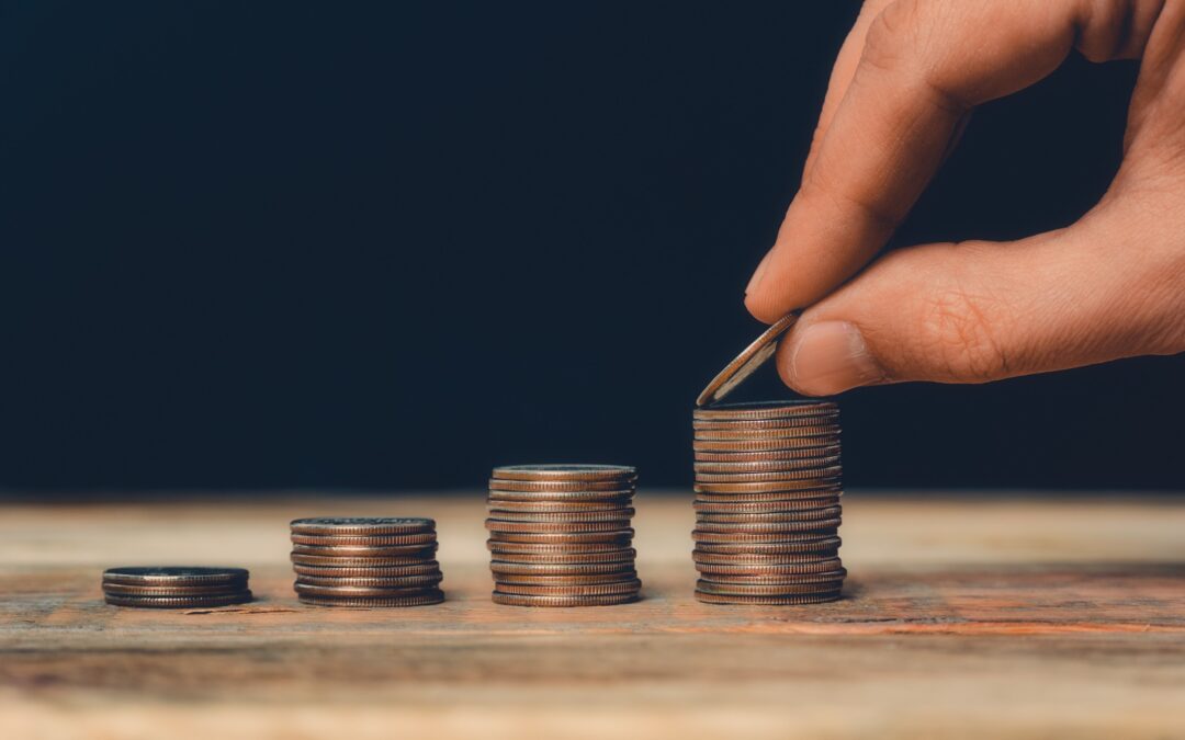 a hand placing a quarter onto the tallest of four stacks