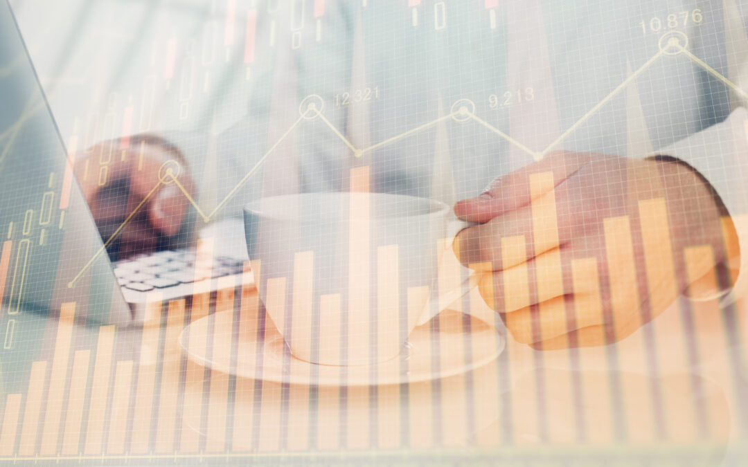 image of a man at a desk with his computer and a cup of coffee and a transparent financial graph is above the image